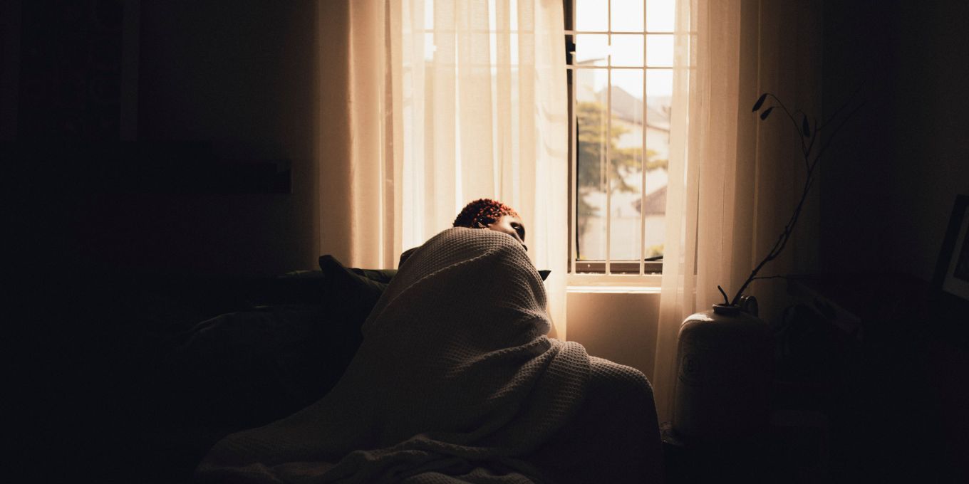 Femme allongée sur un lit, les yeux fermés, dans une chambre calme après un rapport